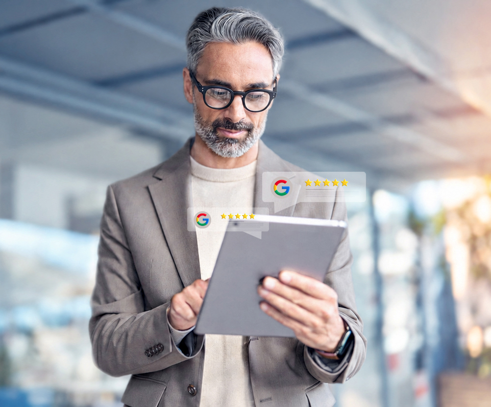 Mann mit Tablet vor eingeblendeten Google-Bewertungen als Symbol für Google-Profil-Optimierung durch FeedbackFabrik